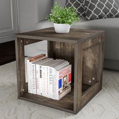 a small wooden cube table with books and a potted plant on it in front of a couch