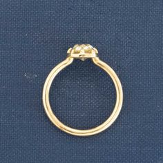 a gold ring with a diamond on the top and bottom, sitting on a blue surface