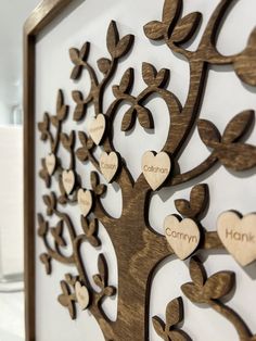 a wooden family tree with hearts hanging from it's sides on a white wall