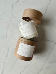 two candles sitting next to each other on top of a white marble countertop with brown paper wrapped around them