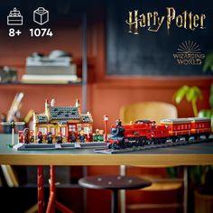 a table with a train set on it and harry potter's house in the background