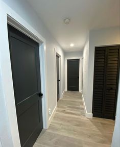 an empty hallway with black doors and white walls