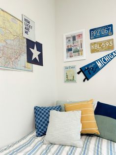 a bed topped with lots of pillows next to a wall covered in pictures and signs