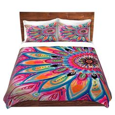 a bed with colorful comforters and pillows on top of it, in front of a white background