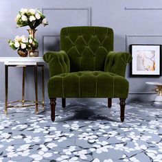 a green chair sitting on top of a floor next to a white flowered table