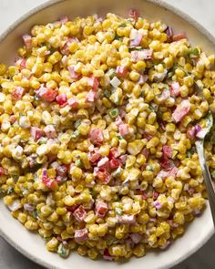 a white bowl filled with corn salad on top of a table