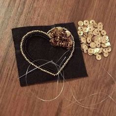 a wooden table topped with lots of different types of beads and buttons on top of a black piece of cloth