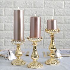 three gold candles sitting on top of a table