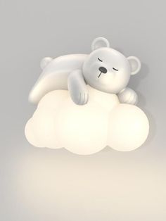 a white teddy bear laying on top of a cloud shaped light fixture with its eyes closed