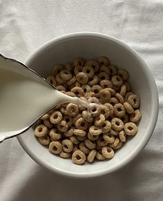 a bowl filled with cereal and milk being poured into it