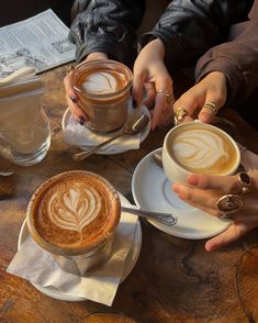 two people sitting at a table with cups of coffee and spoons in their hands