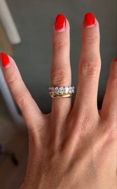 a woman's hand with red nails and a ring on it