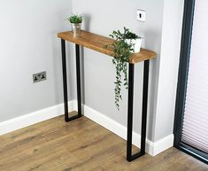 a wooden table with two black metal legs and a potted plant sitting on top