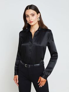 A quintessential blouse in a lustrous silk charmeuse and true black hue. Classic look has a soft, liquid hand and tailored silhouette shaped by sharp sartorial details like a stand collar, long button-cuff sleeves, and back yoke with inverted pleat. An open neckline and curved hem add subtle femininity. A nimble style that works equally well with jeans or skirts. Fastens in front with tonal buttons. | L'AGENCE Tyler Silk Blouse Top In Black Collarless Leather Jacket, Satin Blouses, Denim Blouse, Silk Charmeuse, A Stand, Black Media, Blouse Top, Cuff Sleeves, Silk Blouse