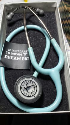 a blue stethoscope sitting in a box with a sign on it that says if you dare to dream, dream big