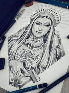 a drawing of the virgin mary holding an umbrella with two crayons next to it