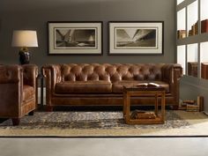 a living room with two pictures on the wall and leather furniture in front of it