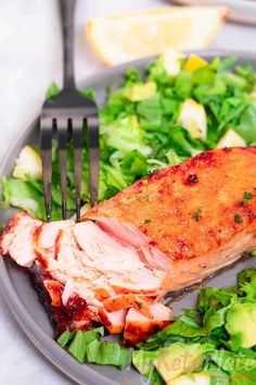 a piece of meat on a plate with some salad and a fork next to it