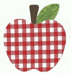 an apple with a green leaf is on a red and white checkered tablecloth