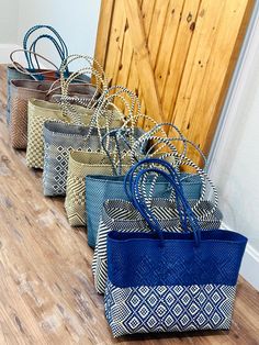 five bags lined up on the floor in front of a wooden door with metal handles