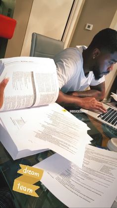 a man sitting in front of a laptop computer on top of a desk filled with papers