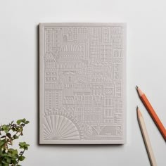 a white paper with a city map on it next to pencils and a potted plant