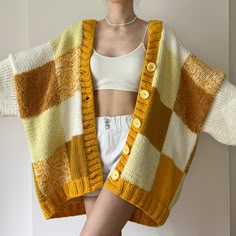 a woman is wearing a yellow and white knitted cardigan