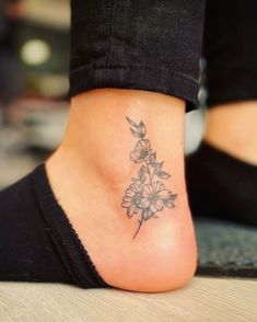 a woman's foot with a small flower tattoo on the side of her leg