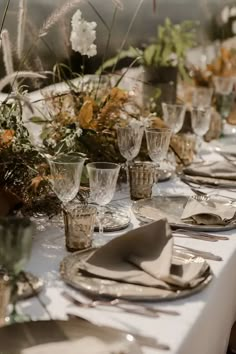 a long table is set with silverware and floral centerpieces for an elegant dinner