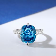 an oval blue diamond surrounded by diamonds on a white surface with a blue and white background