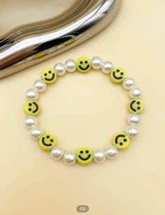 a bracelet with smiley faces and pearls on it next to a heart shaped silver object