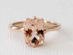 an engagement ring with a pink morganite stone in the center on a white surface