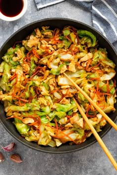 stir fry with chicken, lettuce and carrots in a skillet next to chopsticks