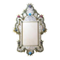 an ornate mirror with flowers and leaves on the frame, hanging on a white wall