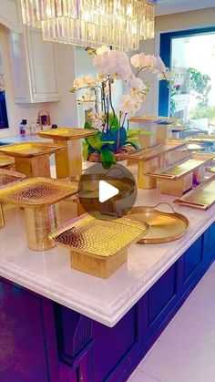 a kitchen counter topped with lots of plates and vases filled with flowers on top of it