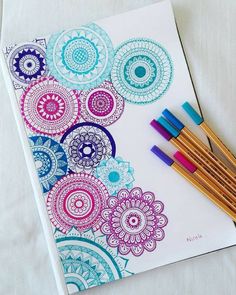 four colored pencils are sitting on top of a coloring book with an intricate design