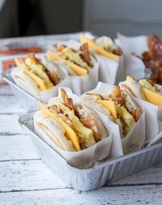 four trays filled with hot dogs covered in cheese and bacon sitting on top of each other