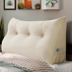 a close up of a pillow on a bed with pictures hanging above the headboard