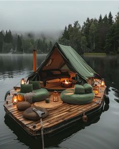 a boat floating on top of a lake filled with lots of pillows and lights next to a tent