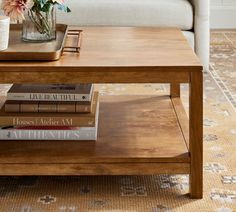 a coffee table with books on it and a vase full of flowers in the center