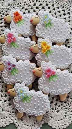 decorated cookies are arranged in the shape of sheeps with flowers on their heads and tails