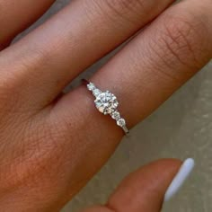 a woman's hand with a diamond ring on top of her finger and an engagement band