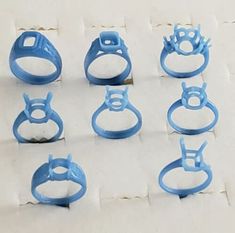 six blue plastic rings sitting on top of a piece of white paper next to each other