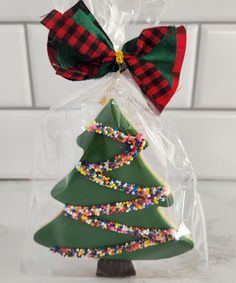 a plastic christmas tree in a bag with a red and green bow on it's head