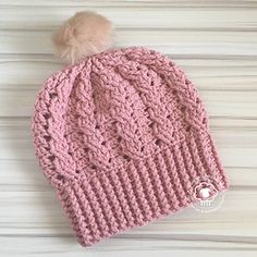 a pink knitted hat with a pom - pom on top