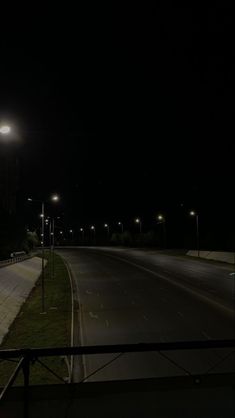 an empty street at night with lights on and no cars driving down the road in front of it