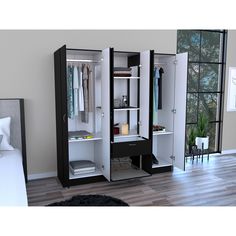 an open closet with clothes hanging on the doors and shelves next to a bed in a room