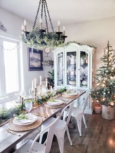 a dining room table decorated for christmas with candles and greenery