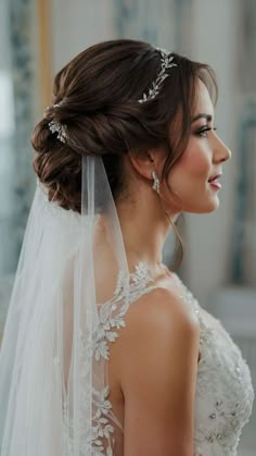 a woman in a wedding dress with a veil on her head, looking off to the side