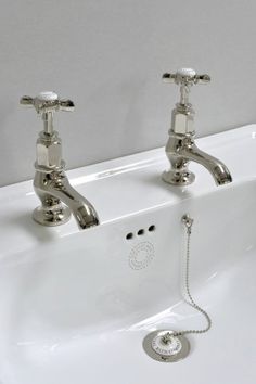 two chrome faucets sitting on top of a white sink